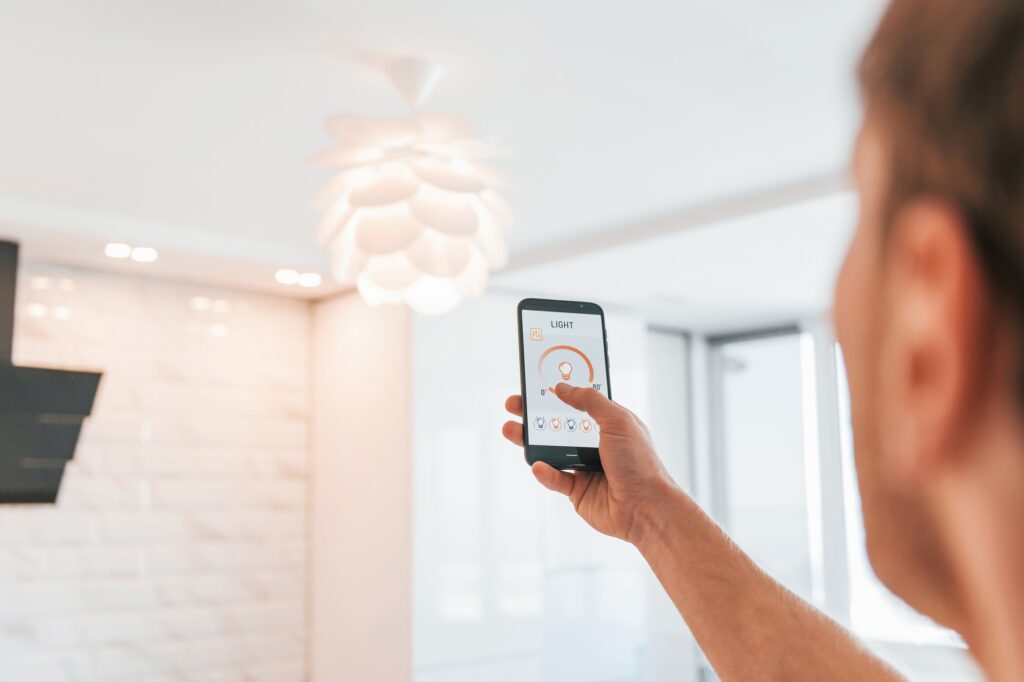 Rear view of adult man that is indoors controlling smart home technology